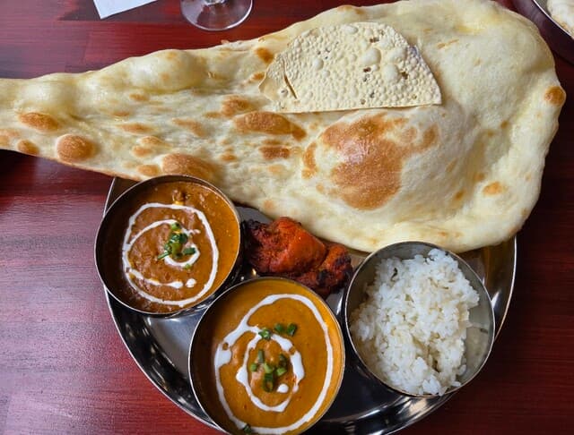 Giant fresh nan with curry, chicken tikka and rice on a steel thali